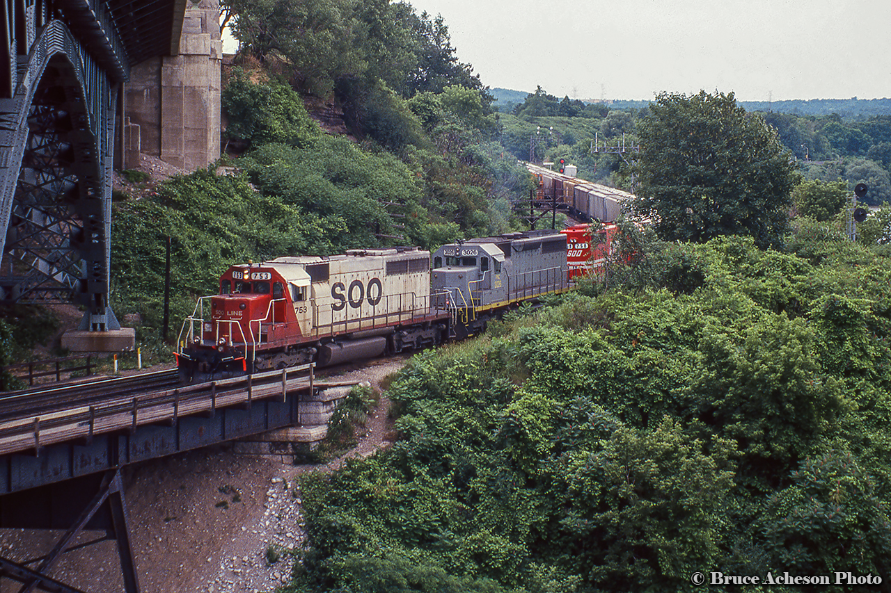 A southbound CP freight, led by a pair of SOO SD40s bracketing PC 3026 pass through Hamilton Junction before the 1995 GO expansion.  Any history on this geep is appreciated.