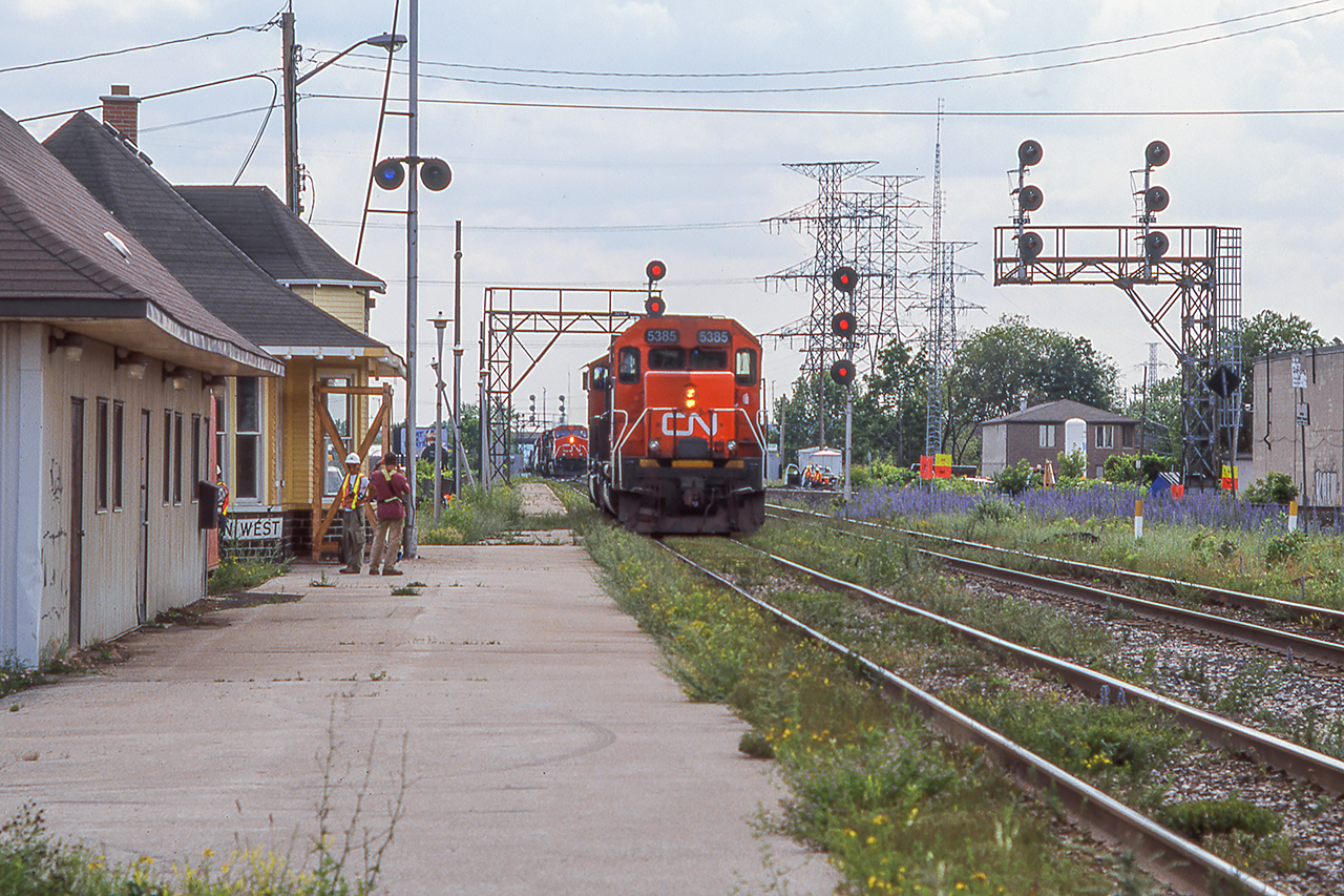 A pair of light engines pause alongside the old Burlington West station waiting for the approaching movement to crossover to the north track and likely onto the Halton Sub.  Crews are seen onsite at the station taking care of some work, potentially prepping for future use.  Estimated date of late summer 2004, as the station would be up and rolling in May 2005.  Today the station sits just a bit further west along Fairview Street and is well preserved by the Friends of Freeman Station.