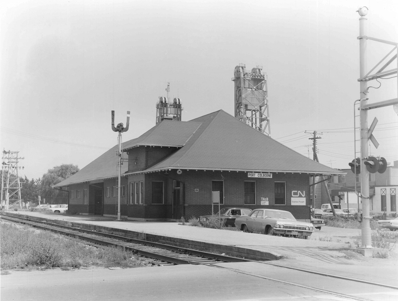 The utilitarian Port Colborne station completed in 1925, replaced a much more interesting building that was demolished to make way for the Fourth Welland Canal construction.  By the time this photo was taken the building housed both the CN Express Freight and the TH&B Freight office (originally at King and Clarence - 2nd floor). Contrast this with Arnold Mooney's photo taken 3 years later and you can see the Station Order Signal in his 1975 shot was moved to the north side of the tracks, and the Bridge #20 Semaphore was replaced by Search Lights http://www.railpictures.ca/?attachment_id=44074. The Dunnville Sub was still active and regularly used up till 1977.  In addition to steam era passenger service, the station was used by the Interurban Trolley NS&T from 1925 till 1959 (1911-1925 the Trolley terminated at the Imperial Bank - Charlotte and West). The King Street crossing appears to have had Flashing Lights and Wig-Wags(barely visible).  Jacob Patterson has posted a great colour image from 1955 at the same location.  http://www.railpictures.ca/?attachment_id=44470.  Garnet Henderson, a WWII veteran spent a couple of years working for the CNR out of Port Colborne in the early '50's... and who was Garnet Henderson... the father to the '72 Canada - Soviet Summit Series Hero - Paul Henderson