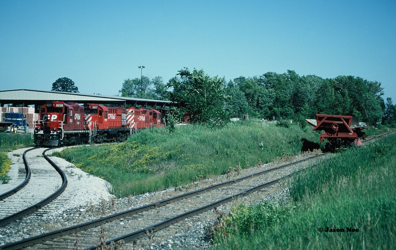 CP 8208, 1117 and 8243 are viewed lifting a car out of the Brampton Brick Limited facility after cutting-away from the CP dump car they had brought from Lambton Yard, which is seen beside the units on the Owen Sound Subdivision in Brampton, Ontario.