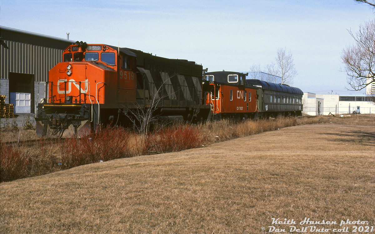 CN GP40-2L(W) 9519 and caboose 79257 handle Mother Parkers private business car #1 "Pacific" on the Ajax Industrial Lead, seen outside the gates near Dowty Road behind Mother Parker's factory in Ajax. This was a likely a special move to either spot or lift the car at the factory.

"Pacific" was a sleeper-buffet-observation car built by CC&F in 1924, and came into prominence when it was used by King George VI and the Queen during their cross-country tour of Canada in 1939, and on the Royal train in 1951. The owner of Mother Parkers Tea and Coffee, Paul Higgins, purchased the car from CN in 1976 (some sources say 1972). His sons who run the company today keep the car stored on a siding at their plant in Ajax, and Pacific still sees occasional use by the company for promotional, travel and fundraising purposes.

Keith Hansen photo, Dan Dell'Unto collection slide.