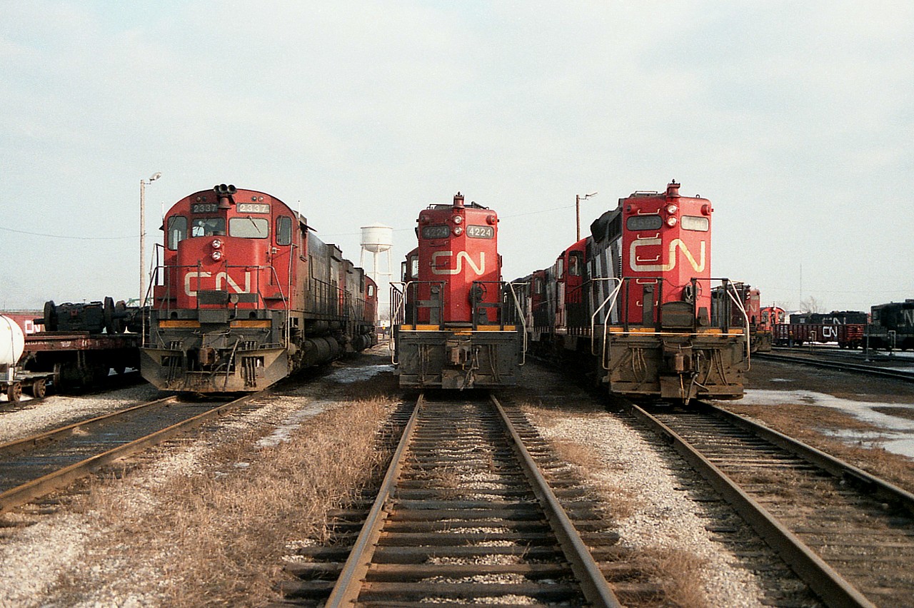 Those old days at Fort Erie.  So much activity. I felt a huge loss when operations ceased there. Most days 8 or 10 locomotives could be found; some in the middle of heavy repair, some fueling and some set up and ready to take a train out when required. I like to think this is what this shot is all about.  CN 2337 along with CN 4224 and CN 4596 are lined up looking ready to go. Did not record the other units. Oh well. Live and learn.
In the background is the old Niagara Region Fort Erie water tower that I used as photo ID.