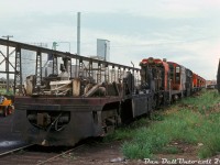 The sad end of CP's Canadian Locomotive Company (Fairbanks Morse) and Baldwin locomotive fleets: the cut-down remains of a CLC C-Liner sits at the end of the scrapping line at Ogden Shops, ahead of a string of Baldwin DS4-4-1000 and DRS4-4-1000 locomotives and another C-Liner, all in the process of being stripped down and eventually cut up. Just a few sandboxes, air tanks, and other components remain above the frame of the lead unit, after the carbody was stripped off and internal components salvaged.<br><br>Going by some spotting features, the lead unit appears to have been CP CFA16-4 4057, likely followed by DS4-4-1000 7073, and CPA16-4 4105. The fifth unit is another switcher, 7068, and the other four mixed in are DRS4-4-1000 units 8001-8004 in unknown order (except the final unit, 8004). All were retired in 1975 during the great purge of CLC, MLW and Baldwin power due to a system-wide downturn in traffic.<br><br>For those inclined, here's a short history of the two oddball fleets:<br><br><u>The FM/CLC units:</u><br><br>Fairbanks Morse (designs licensed to Canadian Locomotive Company in Kingston for Canadian production) made a name for themselves during dieselization by offering their opposed-piston diesel engines (popular for marine use) in their diesel locomotives, producing more power than the competition with fewer cylinders. They offered a wide range of configurations in their streamlined Consolidation line ("C-Liner"), 4- and 6-axle road switchers (H-series, including the most powerful on the market: their 2400hp <a href=><b>"Train Master"</b></a>), and small switching units. Alas, increased competition, reliability issues and decreased orders saw FM exit the locomotive market in the late 50's. Most railroads gradually repowered or retired their FM/CLC locomotives in the 60's, by that time many considered them oddballs, non-standard or unreliable (at least for railroad use). <br><br>CP kept their fleet going much longer than other roads, mainly <a href=http://www.railpictures.ca/?attachment_id=20818><b>in the west</b></a> based out of Nelson BC and Alyth (Calgary AB). However as the 70's rolled around and newer 6-axle mainline power was purchased, plans were in place to gradually retire the CLC fleet: as units failed or faced extensive repairs they were retired, and as part of the phase-out, regular overhauls were reduced or cancelled. A traffic downtown in the mid-1970's accelerated much of this: CP took a bunch of leasers off-lease, parked much of their <a href=http://www.railpictures.ca/?attachment_id=47601><b>MLW 244-powered fleet</b></a>, and retired most of their CLC and Baldwin units.<br><br><i>The end:</i><br><br>In March 1975, the power desk issued an order to round up all the remaining CLC power, dead or alive, and send it to Ogden for storage (CP's parlance was tied up unserviceable/serviceable). A handful of F-units and GP9's were reassigned to Nelson as replacements (but only lasted a few months before Nelson shop itself was closed in June 1975). This included the fleet of H16-44 roadswitchers, and what few C-Liners remained. The CP C-Liners were the last of their kind operating anywhere in North America, and by 1975 only five units remained in service: 4053, 4057, 4065, 4104 and 4105 (4057 officially retired in March because of a frozen engine block, the rest in June).<br><br>There was talk of the monthly cost of maintaining the CLC fleet versus leasers, and plans to keep some of the units stored for possible traffic increases, but ultimately the remaining fleet ended up officially retired June 20th 1975 <a href=http://www.railpictures.ca/?attachment_id=42299><b>and subsequently scrapped</b></a>. Parts off the CLC fleet common to other power (notably MLWs) that CP wanted to reuse were the GE 752 traction motors, air compressors, SKF roller bearings, wheels and axle sets. CP ended up selling roughly two-dozen of the retired unit's engine blocks to an equipment supply company out of Houston TX (as the opposed-piston engines were popular in the secondhand market for marine use). Only three units were spared for preservation: 4065, <a href=http://www.railpictures.ca/?attachment_id=6882><b>4104</b></a> and <a href=http://www.railpictures.ca/?attachment_id=36044><b>8554</b></a>. CP's <a href=http://www.railpictures.ca/?attachment_id=40661><b>three remaining Train Masters</b></a> survived in hump service until they were similarly phased out.<br><br><u>The Baldwins:</u><br><br>The Baldwin fleet was made up of a small handful of DRS4-4-1000 roadswitchers (8000-8012) and DS4-4-1000 switchers (7065-7075), ordered by CP early on to fully dieselize their E&N Vancouver Island operations and the surrounding port area in the late 1940's. Because both Alco/MLW and EMD couldn't guarantee production space for CP's order, CLC brokered a deal for Baldwin to produce the 1000 horsepower units, which were built at Eddystone PA. <br><br>Their isolation out west no doubt contributed to their longevity, but by the 1970's they were oddballs and similarly phased out by CP. Four 8000's were <a href=http://www.railpictures.ca/?attachment_id=46145><b>wrecked</b></a> in 1973, and most of the others still active were retired in 1975. Units 8000-8004 (plus 7068 and 7073) were officially retired June 5th 1975, and 8009-8010 in December of that year, but some of the switchers <a href=http://www.railpictures.ca/?attachment_id=17528><b>lasted a bit longer</b></a> (the final unit retired in 1982). <a href=http://www.railpictures.ca/?attachment_id=22083><b>8000</b></a> was spared for preservation, but 8001-8004 and the two switchers were cut up here at Ogden.<br><br><i>Original photographer unknown, Dan Dell'Unto collection slide.</i>