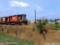 What could be more "Sleepy CP 80's Ontario branchline" than a single CP C424 running back home long hood forward through a small town?<br><br>Sporting white extra flags not relocated from its trip west, CP C424 4217 peddles her wayfreight along the CP Elora Sub heading eastbound through the town of Erin, Ontario. The train has just passed Main Street (Wellington Road 124, trailing off to the right) and is returning back east to <a href=http://www.railpictures.ca/?attachment_id=47132><b>Cataract</b></a> (and likely on to Orangeville), presumably from Fergus where the trailing CN 40' boxcar may have been lifted from the interchange with CN. Erin was Mile 4.5 of the 29.4 mile CP Elora Sub, which branched off the Orangeville Sub at Cataract (Mile 0) and wound its way through Erin, Hillsburg, <a href=http://www.railpictures.ca/?attachment_id=35962><b>Belwood</b></a>, Fergus to end at Elora.<br><br>A 1982 timetable lists the light rail branchline as 25mph maximum speed but with most of the line covered by 20mph speed restrictions. During its final year in 1987, conditions on the line had deteriorated and it was down to 15mph with a number of 5 and 10mph speed restrictions. The all-too-familiar story of low traffic volumes lead to CP abandoning the entire Elora Sub at the end of 1987 (which is now the Elora-Cataract Trailway).<br><br><i>Roger Heed photo, Dan Dell'Unto collection slide.</i>