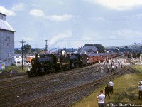 Canadian Pacific Railway D10h's 1098, 1092, and their passenger consist are seen at Orangeville Yard, after arriving northbound on a Buffalo NRHS chapter fantrip operating northbound from Streetsville to Orangeville. Riders are out and about crowding the yard near Town Line crossing, that intersected the north end of the yard. Some have climbed on the tenders of the two D10's, possibly to watch as they take on water at the adjacent water spout.
<br><br>
The top of the original CPR station (since moved and today a restaurant) is visible above the baggage car, and behind that the bunkhouse (burned down in 2006), freight sheds further back, and angled coal tower in the distance near the roundhouse. There were tracks behind the station that lead to coal and oil dealers, grain elevators, the stock pens, all local amenities for a small railway town. In the early 1900's, the original engine house, turntable and coaling platforms used to be located north of the crossing where this photo was taken from, but were relocated to the south at some point in time. One can see part of the Niagara Escarpment rising up in the distance.
<br><br>
What's really interesting about this photo is, judging by some of the people in the shot, it was taken at the same time as <a href=http://www.railpictures.ca/?attachment_id=28583><b>this photo by Bill Thomson</b></a>. One of the figures at the lower right could very well be a young Bill taking his photo, captured by this unknown photographer standing on top of some freight cars nearby.
<br><br>
<i>Original photographer unknown, Dan Dell'Unto collection slide.</i>
<br><br>
<i>More photos of this fantrip:</i><br>
Streetsville: <a href=http://www.railpictures.ca/?attachment_id=33872><b>http://www.railpictures.ca/?attachment_id=33872</b></a><br>
Cataract: <a href=http://www.railpictures.ca/?attachment_id=28108><b>http://www.railpictures.ca/?attachment_id=28108</b></a><br>
Charleston Sideroad: <a href=http://www.railpictures.ca/?attachment_id=36987><b>http://www.railpictures.ca/?attachment_id=36987</b></a>