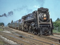 Westbound by Georgetown, CNR U-2-g 4-8-4 6233 (MLW, 1943) heads up Monday - Friday train 11 from Toronto to London, due into Georgetown at 1757h.  The foreground track curving of to the left is the northern section of the Milton Subdivision, running Georgetown to Allandale.  This would become the Beeton Subdivision in 1965 with the creation of the Halton Subdivision.<br><br>In the distance at left is the former <a href=https://images.ourontario.ca/Partners/EHS/ehs00156.jpg>Georgetown Coated Paper Mills Ltd.</a> building which had rail service.  Built in 1910, it would later become Alliance Paper Mills in 1928 before being purchased by Domtar in 1959.  It would carry the name Howard Smith Papers before becoming Domtar Fine Papers Ltd. until closing it's doors in 1978*.  The building survives today by as A-Plus Canada Inc Self-Storage and Applied Wiring Assemblies.  This Bill Thomson shot from 1965 shows the <a href=http://www.railpictures.ca/?attachment_id=18497>spur to the mill at right.</a>  <br><br>*Information from the Esquesing Historical Society.<br><br><i>Original Photographer Unknown, Al Chione Duplicate, Jacob Patterson Collection.</i>