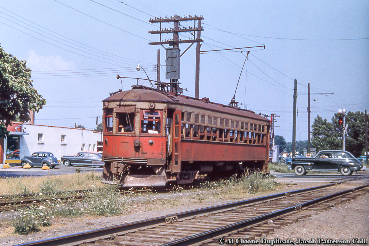 NS&T interurban car 80 has just pulled away from the Port Colborne station (just across King Street) and traffic flow is getting back to normal as the wig wag stops it's sway.  Must be a warm day with the windows and door open to get a breeze.Port Colborne Station, steam power in 1955.Original Photographer Unknown, Al Chione Duplicate, Jacob Patterson Collection Slide.