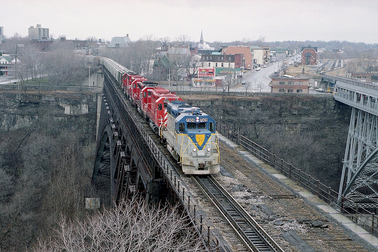 About 8 years ago I posted a shot of this train beginning to cross the Steel Arch bridge from Canada to the USA. I shot it from over the border, standing on the curb of the Robert Moses Parkway.  Well, finally; here is another image.  Having shot the first photo; I ran like blazes (I'm a slow moving blaze) to get another angle.
And this is it.  D&H 7309, CP 5529, SOO 6612, 6601 and 780. Crossing over.
This was heralded as the First International (CP) Grain Train; with three SOO representing the West; the CP 5529 representing the run thru Ontario, and at the NF Montrose Yard D&H 7309 arrived to lead the train over to New York State and the eventual run up the D&H line to Albany.
The weather was drizzling and gloomy.  I was rather hot and bothered. Unfortunately, so were the New York State police, the city police and the border patrol.  But it all worked out in the end, and they let me go........ It is illegal to walk on the elevated part of the parkway, and weird railfan activity just had to be investigated.

It has been 20 years since anything rolled over the Steel Arch bridge. Cost of demolition too high...so it just sits there.  The only active rail left there now is the CN. Station visible on the far right.........