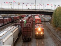 On a very cloudy October evening, CP hotshot intermodal #100 is moving at a leisurely pace through downtown Sudbury with rebuilt AC4400CWM #8016 in the lead. In the background the 4-axle Sudbury Yard job is busy taking apart a cut of cars left by the OVR earlier in the afternoon.