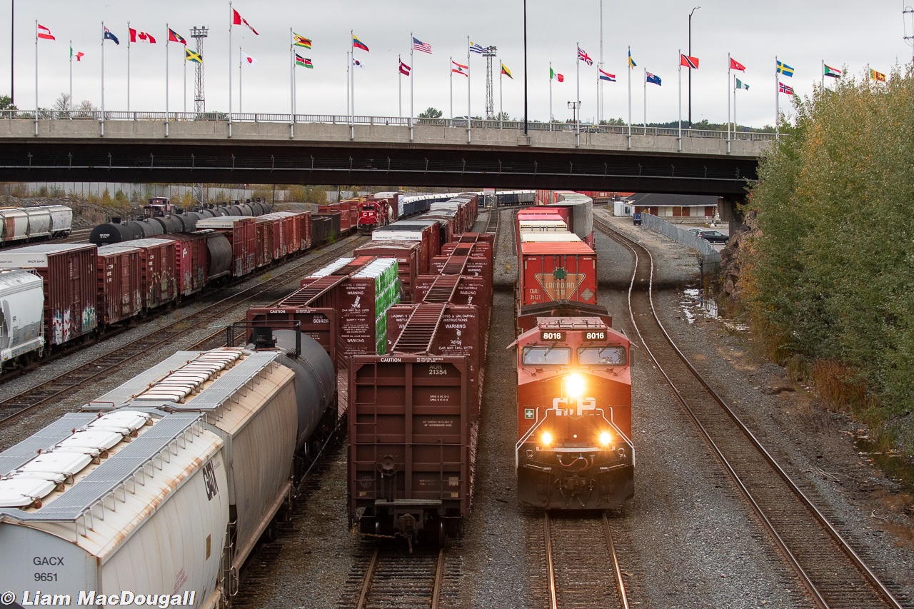 On a very cloudy October evening, CP hotshot intermodal #100 is moving at a leisurely pace through downtown Sudbury with rebuilt AC4400CWM #8016 in the lead. In the background the 4-axle Sudbury Yard job is busy taking apart a cut of cars left by the OVR earlier in the afternoon.