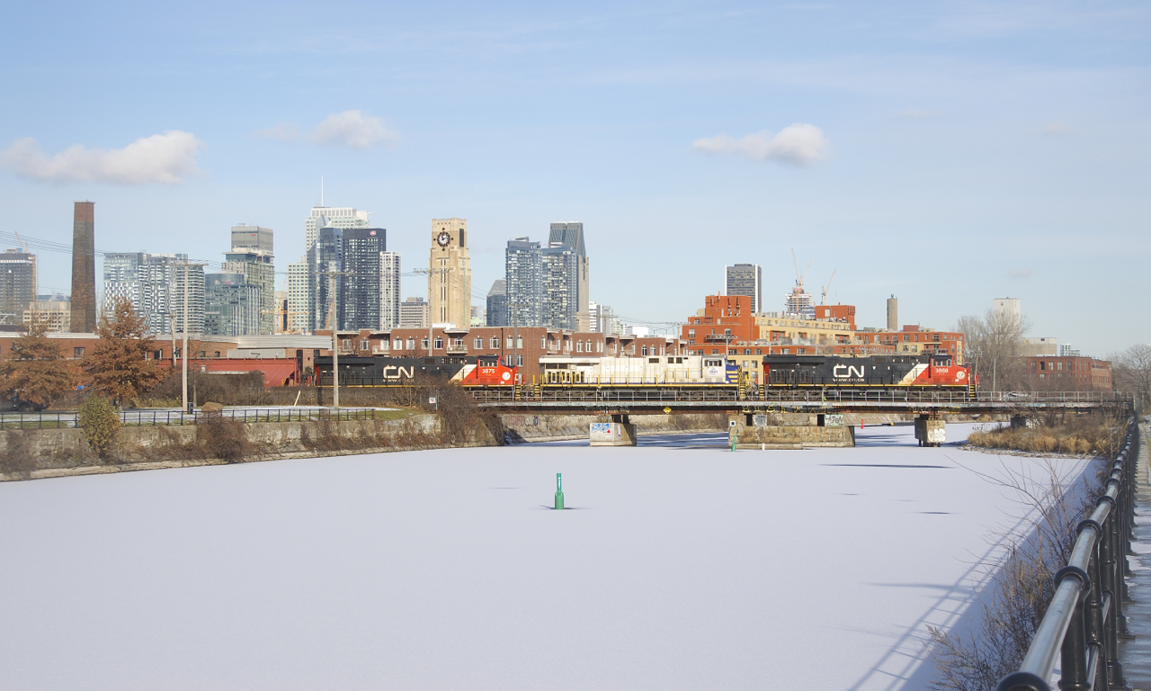 CN B730 crosses the snow-covered Lachine Canal with three units up front (CN 3868, CN 3921 & CN 3875), CN 3883 mid-train and 205 loaded potash cars. Normally this train has the power set up 2X1X1.
