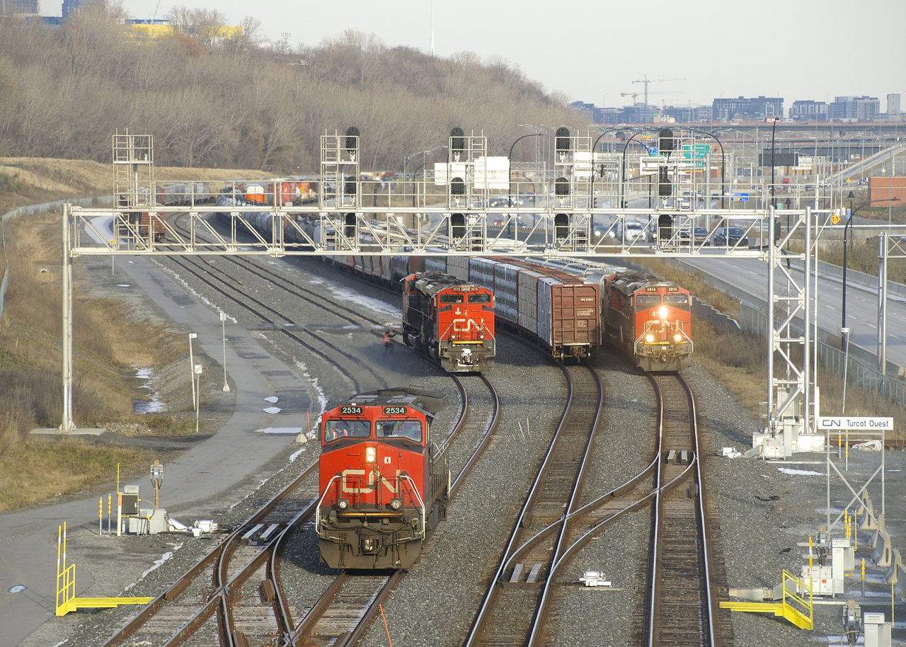 CN 305's leader has just dropped off the two trailing units on the freight track and is now heading west so that it can back onto its train (stopped on the north track). Meanwhile CN 527 is passing on the south track. The fourth track at left (track 29) is occupied as well, with numerours cars parked there.