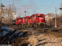 In some beautiful morning sunlight, CP TH11 is crossing Gage Avenue and the diamond with the CN N&NW spur with their cut of cars from Kinnear Yard. A trio of matching paint GP38-2s, each with different ownership history are the power.