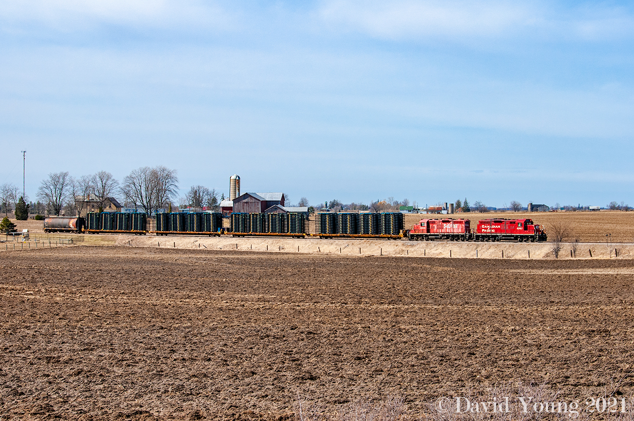 The crew of the day Woodstock yard is rolling through the empty farm fields of Middlesex County on a gorgeous Spring day. GP9u's CP 8201 and STLH 8245 are (timetable) eastbound with 4 loaded frame cars ex Formet in St Thomas destined for the Oshawa GM plant. Bringing up the rear is a hopper destined for Putnam which has been towed the length of the line and back. The crew will set it off and lift five before returning to Woodstock.