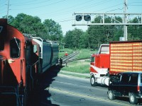 Viewed from the cab of CP 8208, the Moonlight prepares to back over Broadway as traffic waits, including a cab-over truck. The crew was shoving two hoppers into a customer by the Tim Hortons that today is Roechling Engineering Plastics. It might have still been named that during 1997. 

