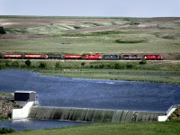 The Assiniboia Tramp departs Swift Current with a train of grain empties for Assiniboia and Shaunavon. The train is passing the water supply dam on the Swift Current Creek.