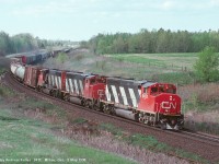 Macmillan Yard - Sarnia train 411 rounding the curve at Mile 30 with a trio of GMD GP40-2W's. CN 9421, CN 9443, and an unidentified third unit are showing the way