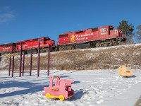 CP T08 crawls past a playground at Burketon Station, with CP 3063 leading a couple GP20C-ECO’s, and some cars destined for Havelock yard. Pretty soon, this train will stop in Pontypool, so the crew can get a coffee at the Country Style before proceeding East on their slow journey to Havelock.