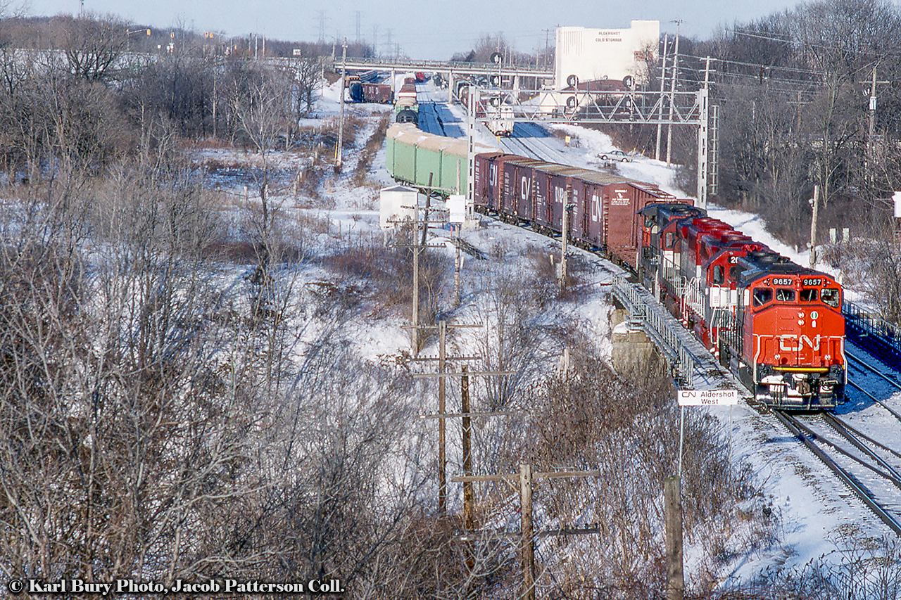 Seen looking east from the Lemonville Road bridge, CN 333 pulls back onto the main after working in Aldershot Yard.  In the consist today is CN 9657 and 9653 bracketing a pair of EMDX GP40-3 lease locomotives, 200, 201.  Both are former GO Transit GP40-2s, numbered GO 725 and GO 726, originally straight GP40s built for the Rock Island Railroad.Shot by multiple photographers, some other views of this train:Before departure from Mac Yard, by David ParkerWorking Aldershot Yard, by Reg ButtonKarl Bury Photo, Jacob Patterson Collection Slide.