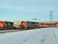 Dash 8-40CM "Draper Taper" CN 2452 and SD75I CN 5675 sit light engine on the yard lead while SD70M-2 passes in the background, rear DP on an eastbound intermodal.