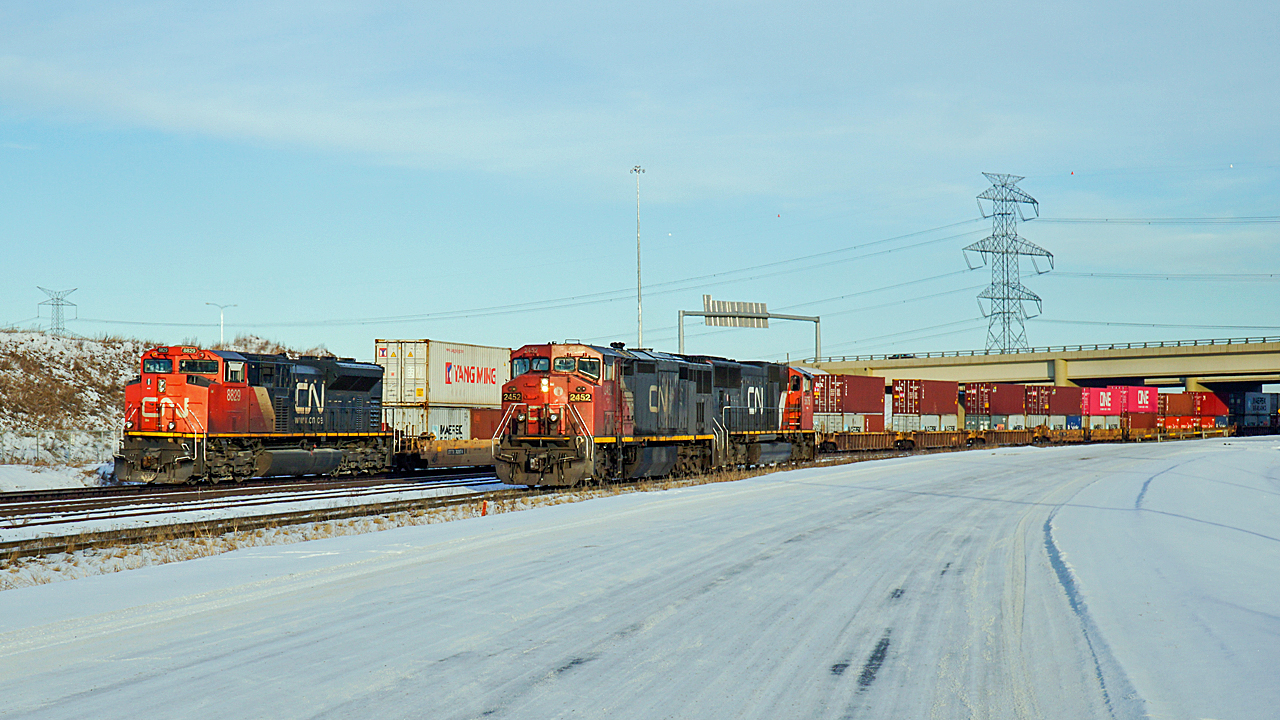 Dash 8-40CM "Draper Taper" CN 2452 and SD75I CN 5675 sit light engine on the yard lead while SD70M-2 passes in the background, rear DP on an eastbound intermodal.