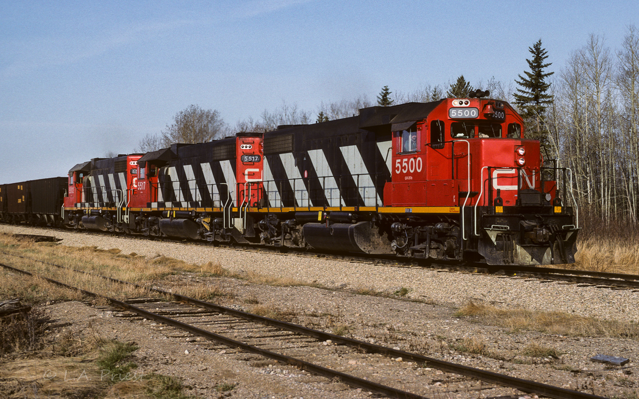 This fresh set of re-painted 5500's has just finished coming around the curve into Kerensky and will be at the Jct. switch to the Lac La Biche in a few more car lengths. A long train of empty hoppers and cab 79795 at the rear. Time 8:00am.