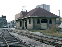 This is a view of the former CN (GTR) station in downtown Waterloo, looking west. This solid brick structure dates from around 1910 and is still standing; now home to a men's wear store. It is located on Regina St. South, a block east of King St. Enhancing the old building now is a caboose on display on the close side (right) and across the way, now single track, is the Laurel Trail; a popular pathway for those out for a walk in town.