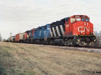CN 421 has just crossed Strange Street in Kitchener as it heads westbound to Stratford with 9668, EMDX 806 and 9508 after lifting and setting-off at the yard. In the background the tower from the Epton Industries Inc. plant at King Street is seen above downtown Kitchener. Later that summer, the company would announce bankruptcy and in turn cease plastics production, eventually closing the facility by December 31 that year, after failing to meet a payment plan. 


