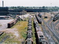 The 1975 traffic downturn that sidelined CP's fleet of <a href=http://www.railpictures.ca/?attachment_id=47531><b>CLC and Baldwin locomotives</b></a> also sidelined much of the 244-powered Alco/MLW fleet as well, including the entire fleet of FA/FB cowl-bodied units. Viewed from the coal tower, lines of stored CP MLW units fill the shop tracks by St. Luc roundhouse, including FA1/FB1, FA2/FB2, FPA2/FPB2, RS3 and RS10 units with stacks capped. The B-units were rounded up first, and the last active FA, 4089, would be shoved into the deadline in November 1975. <br><br> The more modern St. Luc diesel shop is shown on the right, with C424's, RS18's (251-powered units were spared) and SD40-2's. Some switchers are parked on a track adjacent to the deadlines. <br><br> While most of the stored RS3's and RS10's would be reactivated and put back to work for a few more years, the FA/FB fleet would remain stored until official retirement in 1977 and subsequent scrapping. Two units would be set aside for preservation (4090 & 4469). One unit would be converted into an air repeater car (4085 to 1100). A handful of B-units would be de-engined by Angus Shops, renumbered as AN-xx units, and stored again as potential fodder for conversion into robot/radio control cars for Locotrol use out west (only one would ultimately be converted, 4463 to RCC-5 (2nd)). <br><br>Left side from close to far: 8472, 8567, 8482?, 8467? (M&G paint), RS3, 4025?, FA2?, baggage car, caboose<br> Right side from close to far: 4409, 4019, 8582, 4467, 4092, RS3<br> Upper right side: 4095?, FA1, FB2, URS RS3's 15-17, FB1?.<br><br> <i>Original photographer unknown, Dan Dell'Unto collection slide.</i>