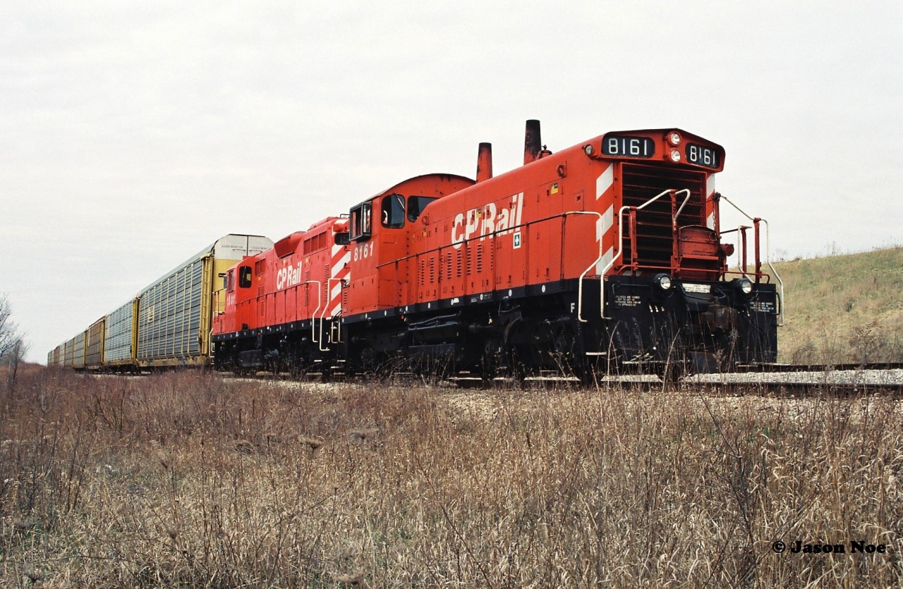 Before there was a large yard at Hagey on the CP Waterloo Subdivision for current auto traffic pre-tripping there was just a couple tracks surrounded by fields in the early to mid-90’s. As new vehicle production from the nearby Toyota manufacturing facility increased and surged over the decade, it necessitated CP building the current yard as well as adding two regular CP assignments from Hagey to service the plant. Here, years before any expansion CP 8161 and 1501 prepare to depart the future Hagey yard at Fountain Street in Cambridge and will head back to Galt yard with a short train of loaded auto racks from Toyota.