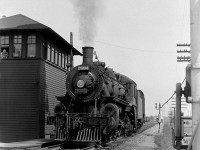 Canadian Pacific G2u "Pacific" 2664 (a Lambton Yard assigned steam engine, possibly on the Trenton Pickup job) works CP's yard at Oshawa, crossing the diamond with the Oshawa Railway under the watchful eye the leverman in the adjacent interlocking tower. Note the overhead catenary for OR's electric operations. Built by CP's Angus Shops in June 1914, 2664 ended her days working out of Lambton Yard until the end of steam, and was scrapped at Angus in March 1961.
<br><br>
The Oshawa Railway was an electric railway owned by GTR/CN that served the town of Oshawa, and interchanged with both CN and CP. It played an important part serving the automotive industry, including northern GM plants in town (notably the GM Oshawa North Plant (truck plant)) that were accessed via streetrunning trackage through town. CP and CN both interchanged cars of automobile parts to the Oshawa Railway for forwarding to the GM plants and associated automotive industries it served. CN de-electrified the line in 1964 and the old <a href=http://www.railpictures.ca/?attachment_id=13773><b>Oshawa Railway electric "motors"</b></a> were retired. CN's GMD SW units were the usual power until most of the "Oshawa Railway Spur" was abandoned in the 1990's. The current OR right-of-way is home to the Michael Starr Trail.
<br><br>
<i>Original photographer unknown, Dan Dell'Unto collection negative (large-format scanned with a DSLR).</i>