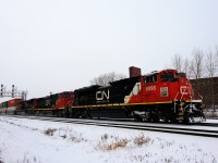 CN 8898 has a sticker on its nose commemorating the 25th anniversary of CN's initial public offering as it leads a 600-axle long CN 120 through the snow.
