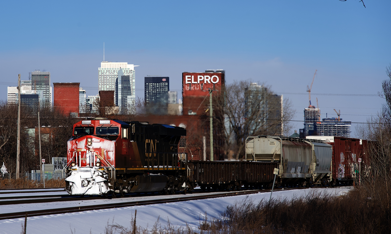 CN 2811 has a lot of snow on its nose as it leads CN 305 past the skyline of downtown Montreal.