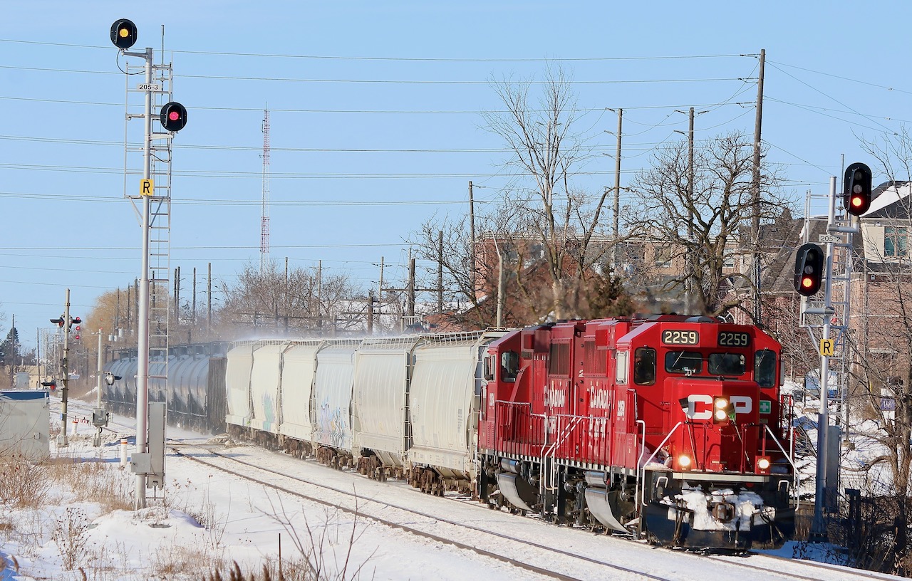 Large snow piles can be a railfans best friend in the winter months. It is nice not having to fight with chain link fences for once, even if it is only for a few months. While GMTX 333 seems to have taken up permanent residence in Streetsville yard it is still nice to follow T14 around when time allows. The oversize signal on the south track at the GO station looks a little out of place here and even has different heads then the one on the north track. This is mainly due to visibility issues from the curve to the east of the station and the height of the station platform overhang. Here T14 heads home to West Toronto after working both Streetsville and Hornby. The scrap gondola is a bit out of place here but I believe it was left several days earlier by an eastbound train after it set off the hot box detector.