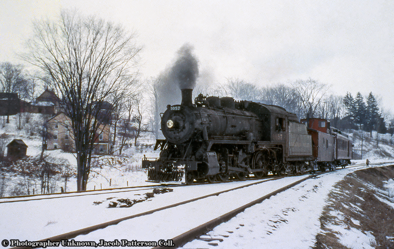 Long before becoming a well known excursion locomotive, CPR 1057 was just another D10h 4-6-0 working the branch lines of southern Ontario, on this day, handling mixed trains 715/716 on the Walkerton branch. Seen here on arrival from Orangeville approaching the small yard at Walkerton, 1057 will run around the consist and complete any work in town before departure back to Orangeville.Canadian Pacific's Walkerton Subdivision originated as the Walkerton & Lucknow Railway, incorporated in 1904, construction would begin in 1906 and be fully completed in 1908, splitting off the Owen Sound Subdivision at Saugeen Junction and running west via Durham and Hanover to it's namesake town. The CPR would lease the railway beginning November 1906, and the line would open for service in August 1908. Per a 1909 timetable, there were at one time four scheduled passenger trains over the line daily except Sunday, plus other freight movements. During the 1930s, effects of the Great Depression were felt on most branch lines and passenger services were reduced or eliminated. By 1932, the Walkerton branch passenger services were replaced with a daily except Sunday mixed train. Service on the line continued as such until August 3, 1957, when mixed trains 715/716 would be discontinued, leaving the line freight only. Mixed trains 753/756 to Teeswater also ran their last miles on this day. July 1983 saw abandonment of the Walkerton Sub from a point west of Hanover to Walkerton, with the condition that ownership and operations of industrial trackage within Hanover would be transferred to CN. By transferring service to CN, CP would be allowed to abandon the remainder of the Walkerton Sub from Saugeen to Hanover. By 1984, the Walkerton Subdivision would be abandoned, the switches at Saugeen Junction removed by October, and the entire line removed by December of that year.  *Information from a number of UCRS Newsletters.Original Photographer Unknown, Jacob Patterson Collection Slide.