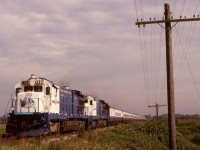 Rocky Mountaineer’s predecessor was the Great Canadian Railtours Company, and they started with a pair of eventually-repainted ex-ATSF GE B37-7 units for power, seen here westbound at 1550 on Wednesday 1992-08-19 with 12 cars in Pitt Meadows and about to cross Kennedy Road then approach the CP Pitt River bridge.<p>The open farmland on the left side of the photo is now CP’s Vancouver Intermodal Facility, the pole line is long since history, and a CTC crossover is now at the location of the second unit.