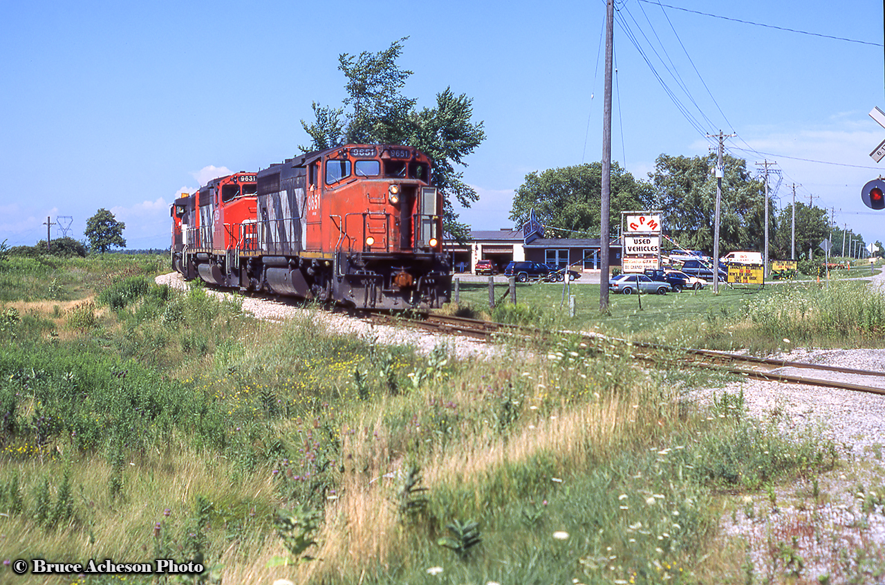 A trio of CN Canadian Cab units head south at Garnet about to cross Highway 6.  RPM Used Vehicles dealership is in the background.  CN 9651, sold in 2000 to Helm Financial, later to Alabama & Tennessee River Railway 9651.  CN 9631 sold to Alstom in 2001, sold to Yadkin Valley Railroad in 2003, to WATCO in 2004, still operating as WATCO 4021.