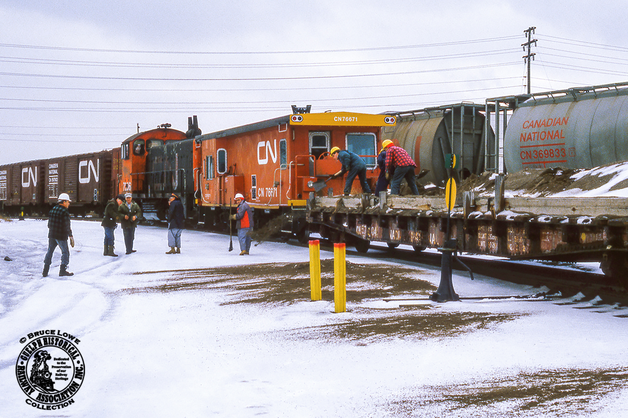 Its not just roads and sidewalks that need salt or sand to keep their surfaces safe, railyards need it too.  On a visit to Mimico Yard in February 1985, Bruce Lowe captured a yard crew dropping sand along one of the ladder tracks, shoveling it off the deck of a flatcar modified with timbers to keep the sand on the car.

GMD SW900 7206, built 1953, would be renumbered to 7906 very soon, along with the rest of the series, to clear the 7200 series for GP9RM rebuilds, the earliest of which appeared in June 1985.