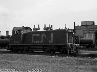 A crew member hops back aboard CN SW1200RS 1316 as it switches the trackage around the Hymus Road area of CN's <a href=http://www.railpictures.ca/?attachment_id=34884><b>GECO Branch</b></a>, in the industrial "Golden Mile" area of Scarborough. There was a <a href=http://jpeg2000.eloquent-systems.com/toronto.html?image=ser12/s0012_fl1968_it0095.jp2><b>small yard</b></a> (middle left of the aerial) here at the time, located along Hymus Road between Warden Avenue and Sinnott Road. In the background, tank cars are spotted by the Chemtura plant, one of the many <a href=http://www.railpictures.ca/?attachment_id=45826><b>customers</b></a> in this post-war industrial area that used rail service. Today, much of the sprawling trackage and sidings are gone, and CN only serves a small handful of customers off the GECO branch.<br><br>To the north of Eglinton, CP served customers off their <a href=http://www.railpictures.ca/?attachment_id=45682><b>Scarborough Industrial Spur</b></a>.<br><br>CN's distinctive GMD-built SW1200RS units often made appearances in local switching duty alongside their smaller SW8/900/9/1200 siblings. They differed from the other SW's as they featured Flexicoil BB trucks that were more suited for mainline road use, end drop-steps and MU connections for multiple-unit operation, and were equipped with 3-chime air horns, large numberboard housings and class lights at either end. CN's usual spark arrestors were either added after delivery on early units, or as-delivered on later units.<br><br><i>Original photographer unknown (possibly Bill Grandin), Dan Dell'Unto collection negative.</i>