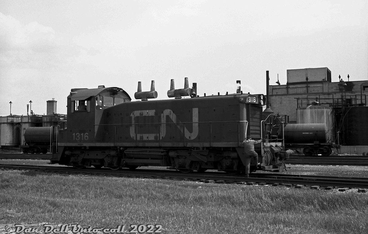 A crew member hops back aboard CN SW1200RS 1316 as it switches the trackage around the Hymus Road area of CN's GECO Branch, in the industrial "Golden Mile" area of Scarborough. There was a small yard (middle of the image) here at the time, located along Hymus Road between Warden Avenue and Sinnott Road. In the background, tank cars are spotted by the Chemtura plant, one of the many customers in this post-war industrial area that used rail service. Today, much of the sprawling trackage and sidings are gone, and CN only serves a small handful of customers off the GECO branch.To the north of Eglinton, CP served customers off their Scarborough Industrial Spur.CN's distinctive GMD-built SW1200RS units often made appearances in local switching duty alongside their smaller SW8/900/9/1200 siblings. They differed from the other SW's as they featured Flexicoil BB trucks that were more suited for mainline road use, end drop-steps and MU connections for multiple-unit operation, and were equipped with 3-chime air horns, large numberboard housings and class lights at either end. CN's usual spark arrestors were either added after delivery on early units, or as-delivered on later units.Original photographer unknown (possibly Bill Grandin), Dan Dell'Unto collection negative.