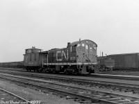 Alco and MLW switchers were typical local and yard power for the steam and early diesel eras, CN and CP both purchased many of the little 660- (S3) and 1000-horsepower (S2, S4) units in the 40's and 50's to replace their smaller steam power. Here, CN S2 8135 sports the brand new "CN" noodle logo and branding, sitting in Danforth Yard with wooden caboose 78429(?) bearing the old "Serves All Canada" wafer logo. Visible in the yard behind is a long cut of "GS" drop-bottom gondolas, perhaps for aggregate service to/from the nearby aggregate industries that were located in the Scarborough area. Also visible is a 40' double door automobile boxcar, and an outside-braced wooden boxcar.
<br><br>
CN's Danforth Yard was once a large freight yard in Scarborough (east end Toronto), at the top of a grade that required pushers in the steam era. It declined in importance after the steam-era due to opening of CN's new modern Toronto (MacMillan) Yard in the mid-60's, and the gradual decline of local rail customers. In its later years it served as home for CN's maintenance of way department and their work equipment. The yard was removed and site redeveloped into housing sometime in the late 90's.
<br><br>
Upon retirement in 1975, CN 8135 was donated to the Canadian Railway Historical Association, Toronto & York Division (CRHA T&Y) and repainted/restored in its original paint and number as CN 7988, and put on display at the CRHA's harbourfront museum near Queen's Quay and Bathurst in Toronto. When the museum was moved out in the late 80's, all equipment was removed and eventually dispersed or disposed of. 7988 apparently had condemned wheels, and was scrapped.
<br><br>
<i>Original photographer unknown, Dan Dell'Unto collection negative (large-format scanned with a DSLR).</i>