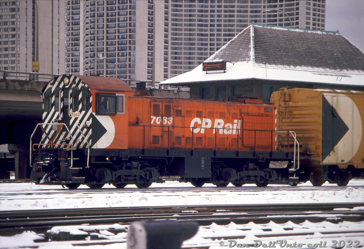 34 years old and into her final years of service, CP S2 7063 rattles past the Scott Street interlocking tower east of Union Station, either busy switching CP's nearby John Street yards, or working a local or transfer run through the Toronto Terminals Railway corridor downtown. The multimark of insulated heated 40' boxcar 35876 is visible, painted "Action Yellow" as per the usual CP Rail colour guidelines (insulated boxcars, cabooses and work equipment were typically painted yellow).

The illuminated arrow sign on the roof of Scott Street interlocking tower (and John Street tower) was there to notify passengers on inbound trains as to which side of the train the doors would be opening on. The sign on Scott St. lingered on, unused, into recent years.

Robert Kentie photo, Dan Dell'Unto collection slide.