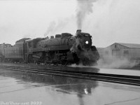 <b>Steam-Diesel Doubleheader:</b> Caught in a fall downpour, Canadian Pacific G3g 2424 doubleheads an eastbound freight with RS18 8738 and another sister unit heading eastbound past the station platforms at Leaside. 2414 was likely working assist duties, helping the diesel-powered freight climb the Belleville Sub grade from Leaside up to Agincourt.<br><br>8738 was only two years old at this time (built by MLW in 1957), but 2414, built by CLC in 1943, was running out her final years in service with the rest of CP's remaining steam power. Retired sometime in 1960 at the end of the steam era, she would be scrapped at Angus Shops in April 1961.<br><br>In the background is a building for Sheridan Equipment Co. Limited (located adjacent to <a href=http://www.railpictures.ca/?attachment_id=44459><b>James N. Scott</b></a>), with the rear of a construction scraper visible. The trackside doors hint at an adjacent rail siding. Both buildings are still present at Leaside today.<br><br><i>Original photographer unknown, Dan Dell'Unto collection negative (large-format scanned with a DSLR).</i>