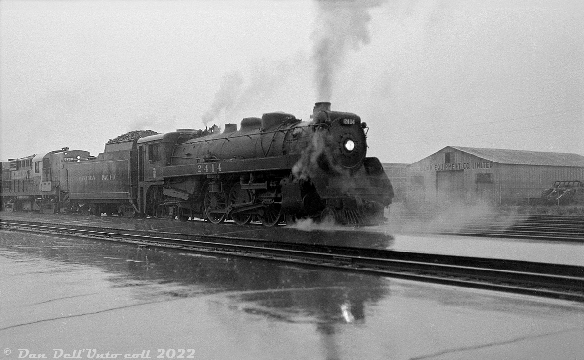 Steam-Diesel Doubleheader: Caught in a fall downpour, Canadian Pacific G3g 2424 doubleheads an eastbound freight with RS18 8738 and another sister unit heading eastbound past the station platforms at Leaside. 2414 was likely working assist duties, helping the diesel-powered freight climb the Belleville Sub grade from Leaside up to Agincourt.

8738 was only two years old at this time (built by MLW in 1957), but 2414, built by CLC in 1943, was running out her final years in service with the rest of CP's remaining steam power. Retired sometime in 1960 at the end of the steam era, she would be scrapped at Angus Shops in April 1961.

Original photographer unknown, Dan Dell'Unto collection negative (large-format scanned with a DSLR).