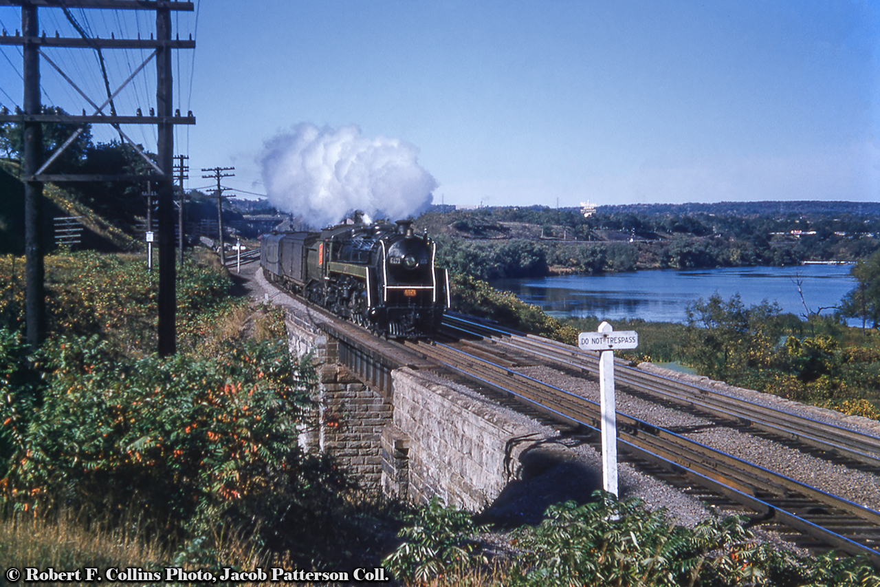 Train 83, led by CNR U-1-f 6071, a 1944 product of MLW, crosses the Desjardins Canal on its journey from Toronto to Niagara Falls.  Due into Hamilton James Street station at 1440h, the train will change numbers from 83, the westbound trip from Toronto, to 86 for the eastbound trip to the Falls.  6071 would be scrapped in June 1961.Originally constructed as a swing bridge in 1855 by the Great Western Railway, Canada’s third worst railway disaster would occur on this bridge on March 12, 1857, when a Hamilton-bound train with a broken axle tore through the bridge, plunging into the canal below.  59 souls perished.  (More information from the Hamilton Public Library HERE.).  The bridge would be rebuilt in its current form in 1859, though the solid bridge no longer allowed large ships to access Dundas via the canal, eliminating the town as a port facility.  Modifications would come again in 2016 with the installation of a third span for Metrolinx expansion into Hamilton’s West Harbour GO station.Note the overpass just above the head end cars: Valley Inn Road, which, as seen in this 1959 aerial, crossed over the CNR “cowpath” and CPR Goderich Sub just south of York Boulevard, joining it just west of the rail lines.  Further off to the right near Bayview Junction, the large sign overlooking the scene sits just north of the intersection of Highways 2 and 6, today the intersection of York Boulevard and Plains Road West and can be seen much closer in this circa 1960 shot.  “NEILSON’S JERSEY MILK CHOCOLATE, THE BEST MILK CHOCOLATE MADE.”Robert F. Collins Photo, Jacob Patterson Collection Slide.