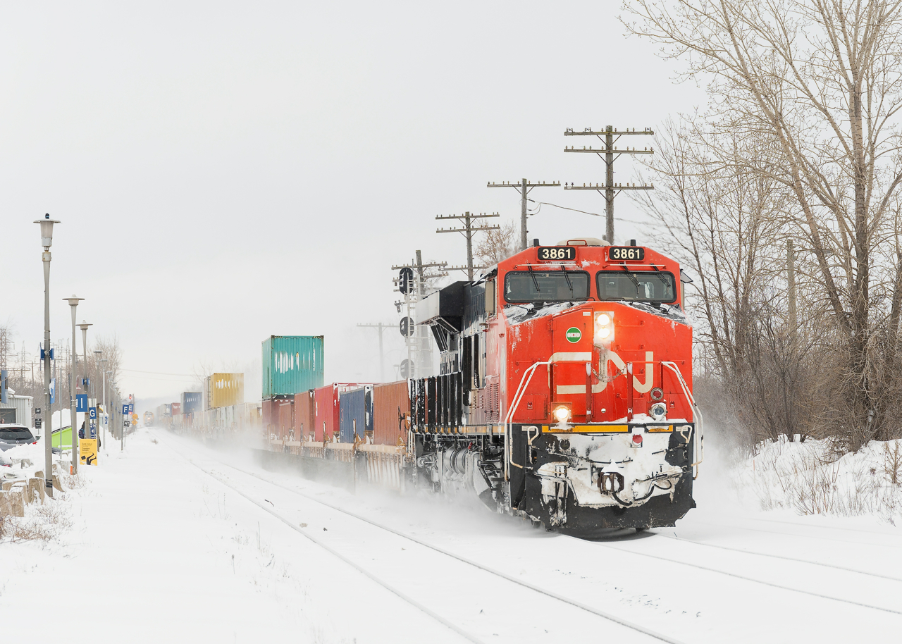 CN 108 is passing through Dorval Station with CN 3861 up front and CN 2220 on the tail end. In the distance, VIA 24 is approaching on the south track.