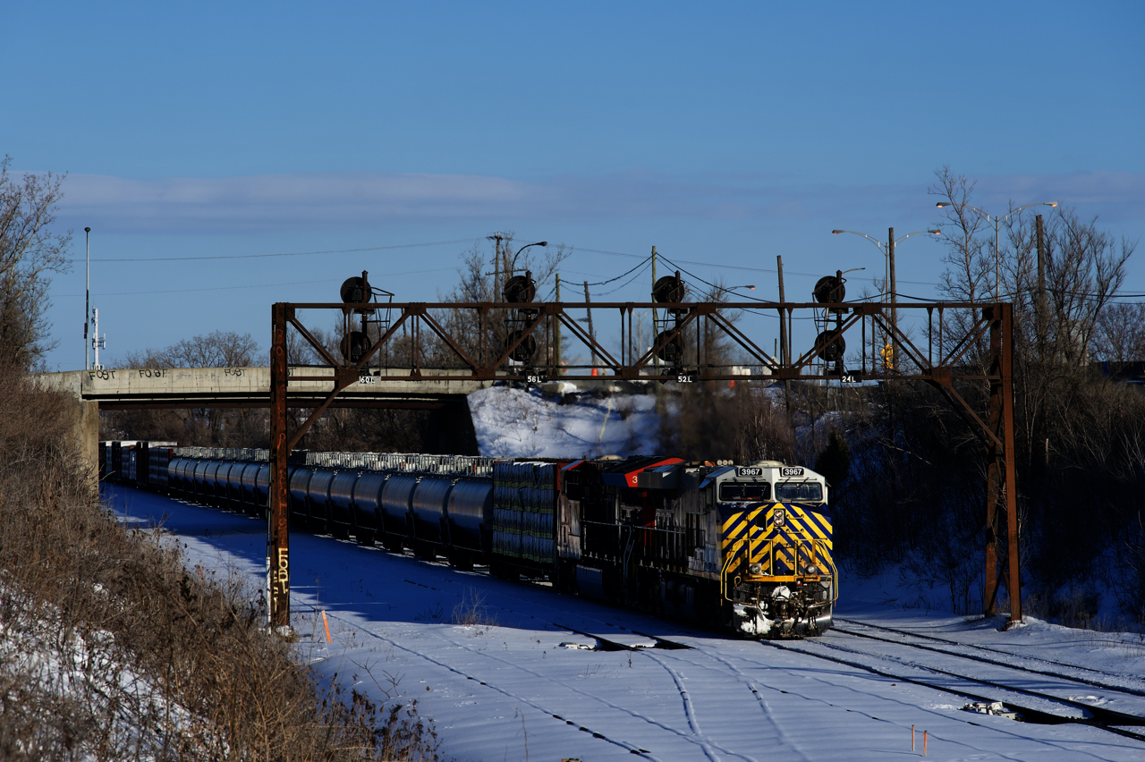 After holding for CN 322 to exit Taschereau Yard, CN 401 is on the move and about to enter the yard. Power is CN 3967 & CN 3250 and a string of TankTrain cars are up front.