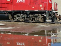 Area "H" reflections. After spending a hour along the Area H spur in Etobicoke on Saturday, all I could think of was the scale model creations of layout maker Lance Mindheim. He is well know for his real to life industrial spur HO scale switching layouts, such as the Miami spur and Los Angeles spur. These spurs along with CP's Area H consist of numerous rail served local industries, (some abandoned). Rails imbedded in the roads and parking lots they encounter as well as along active roadsides. While this image doesn't do justice to most of that, just watching the crew do their work left me looking forward to my next visit. Unfortunately the local has to back southward down the spur, making decent sunny day shots hard to come by, at least with the power leading.  Nevertheless the area is worth a visit, typically Tuesday, Thursday and Saturday. Here the train is seen reflecting in a puddle deep along the spur as they switch out tank cars.