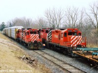 Two friends and I went out in March 2004 to the Ingersoll/Woodstock area for trains, one of my favourite spots: CN and CP are close by along with NS 327/8. Plus you had the frame train, an afternoon favourite as they would usually come during the afternoon lull. Imagine our surprise when the Frame Train is getting a clearance on the CPR St. Thomas sub from the RTC then they say "Proceed from Mile 0.7 to East Siding Switch Beachville, clear main track".... clear main track? The frame train? For what? Let's go.... We didn't have to go too far and with TK12 coming back from CAMI with a long cut of cars, the Frame Train had to take the siding as they would fit. From what I recall meets here were very rare and I'd only have heard of it on two or three occasions in this era basically per year. Photo notes:Nikon F65, Scanned (by Jacob) from a print and originally on Fuji Provia film. It was this outing and the next one in Sudbury later that month that basically pushed me to get a DSLR in a couple weeks time and never look back.<br><br>Bonus: Here's us watching it all unfold by David Graham: <a href=http://cdlu.railfan.ca/cgi/img.cgi?2004-03-06.7948.Beachville.jpg&size=0 target=_blank>here </a> and a <a href=http://cdlu.railfan.ca/cgi/viewer.cgi?2004-03-06.7951.Beachville.avi.jpg target=_blank>Video of the meet too</a>. These were the days.... and for the most part this line was basically ignored by most - this was every day stuff.