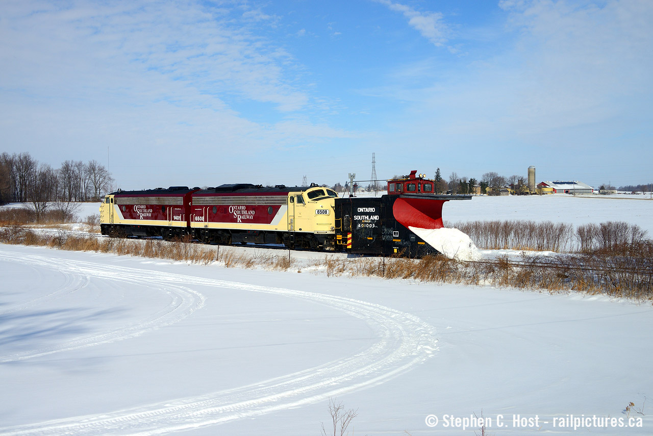 If there's one thing about the OSR and plowing, it's fish in a barrel. All you have to know is they're running and you can at least get *something*. Thanks to a well timed social media post, I heard they went from Woodstock to St. Thomas first thing in the morning with the Port Burwell sub to Tillsonburg to come later. Knowing a St. Thomas run takes hours, I knew I had a chance. I timed it just right so I could arrive as they were heading south, and lucky for me after a cloudy morning the sun came out at lunchtime for their relatively short (less than an hour) journey to Tillsonburg. Pictured for the first time a pair of repainted F units are on a plow as they head south passing snowmobile trails approaching the DeBruyen Farm. There was very little (snow) action to be had, but the F units and plow sure look purdy (heh heh heh) in the sun.